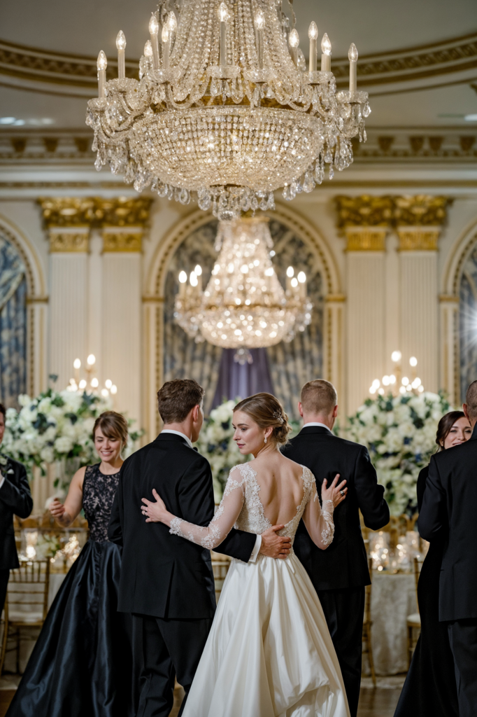 Bride and groom share their first dance beneath opulent chandeliers, celebrating their love at an elegant ballroom wedding reception.